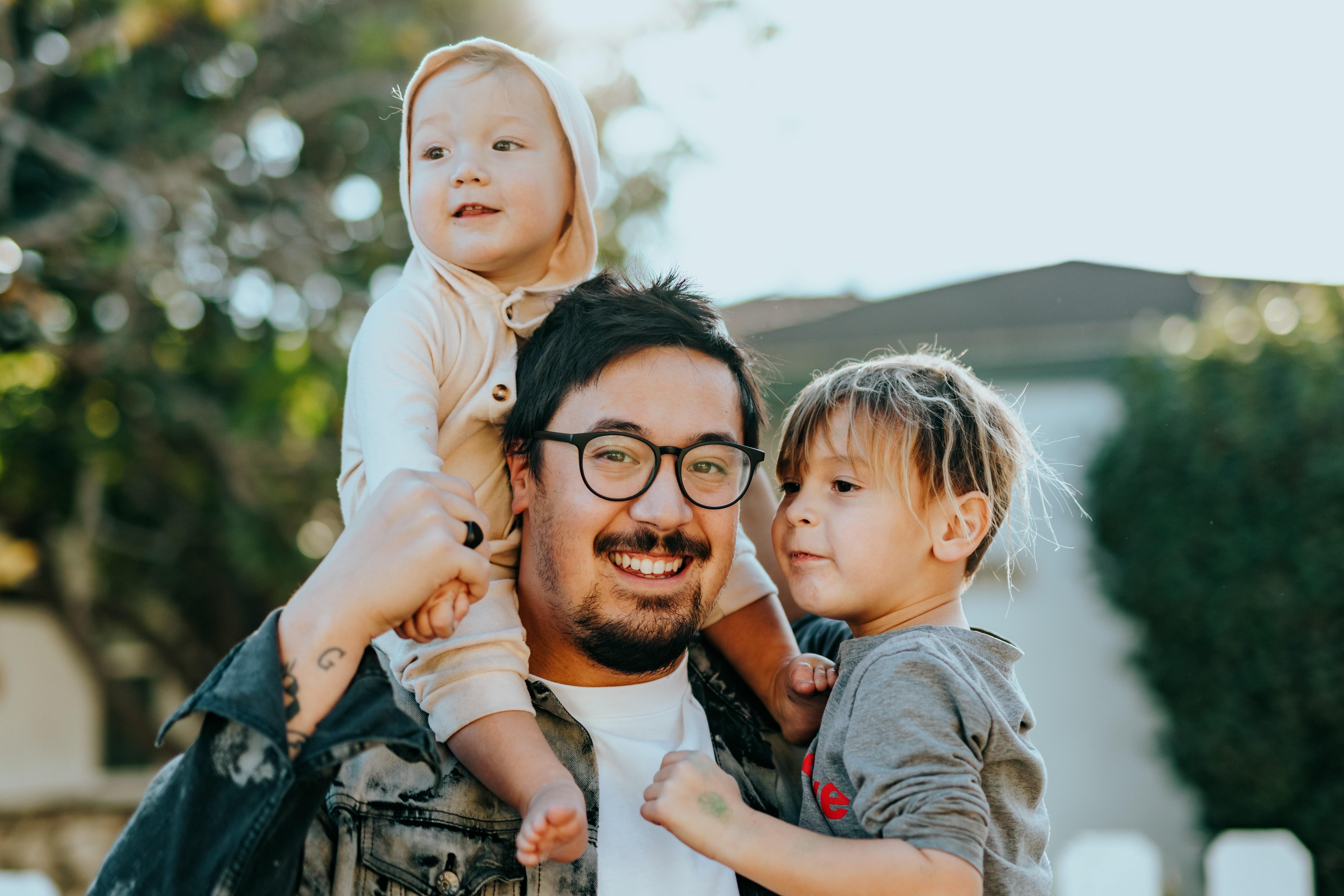 Dad smiling with two children in his arms