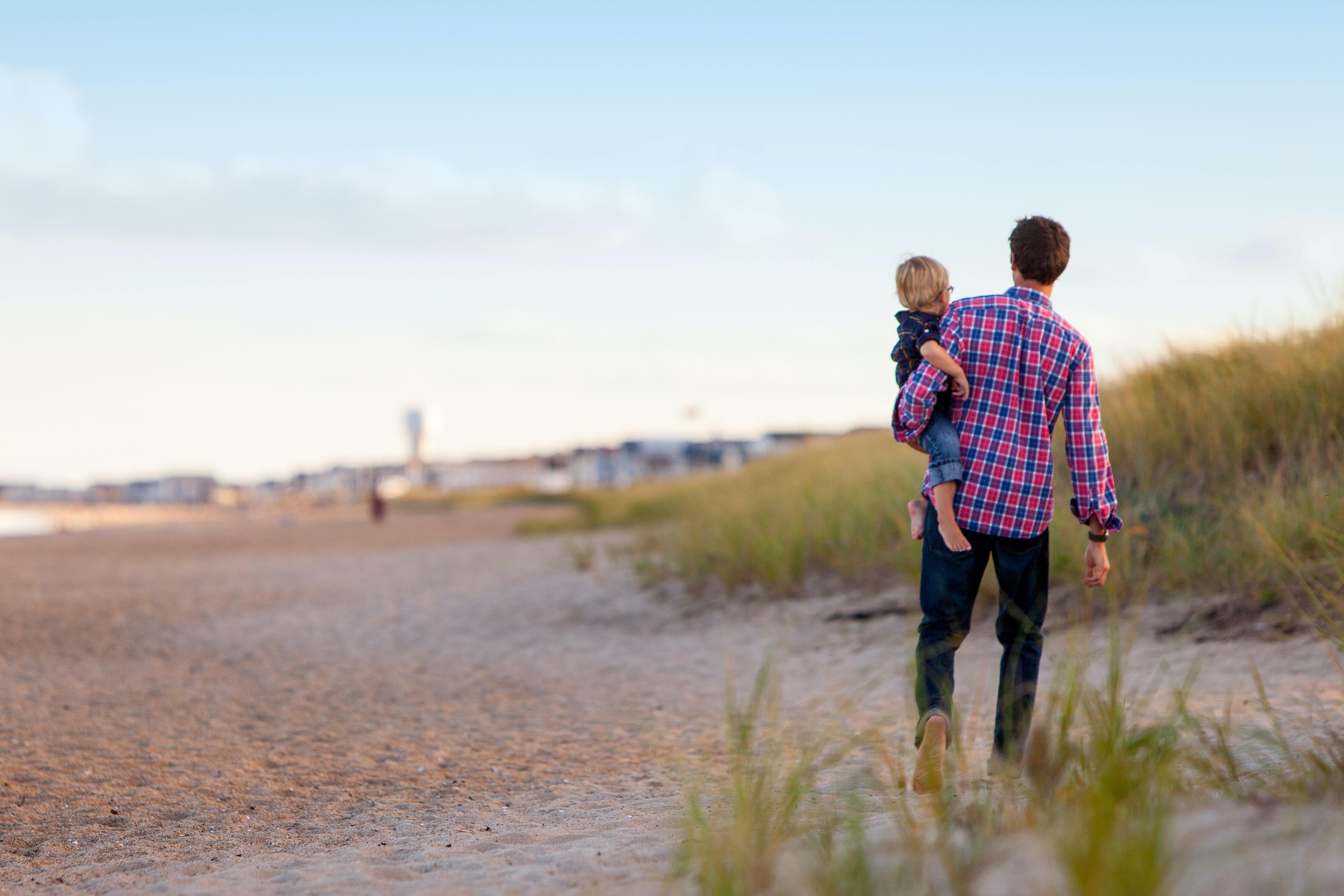 Dad holding child walking on the beach